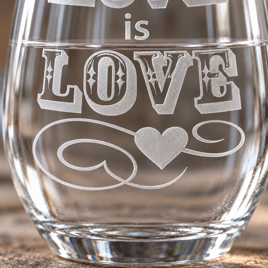 Love Is Love etched stemless wine glass. Close view of the heart and flourish beneath the lettering.