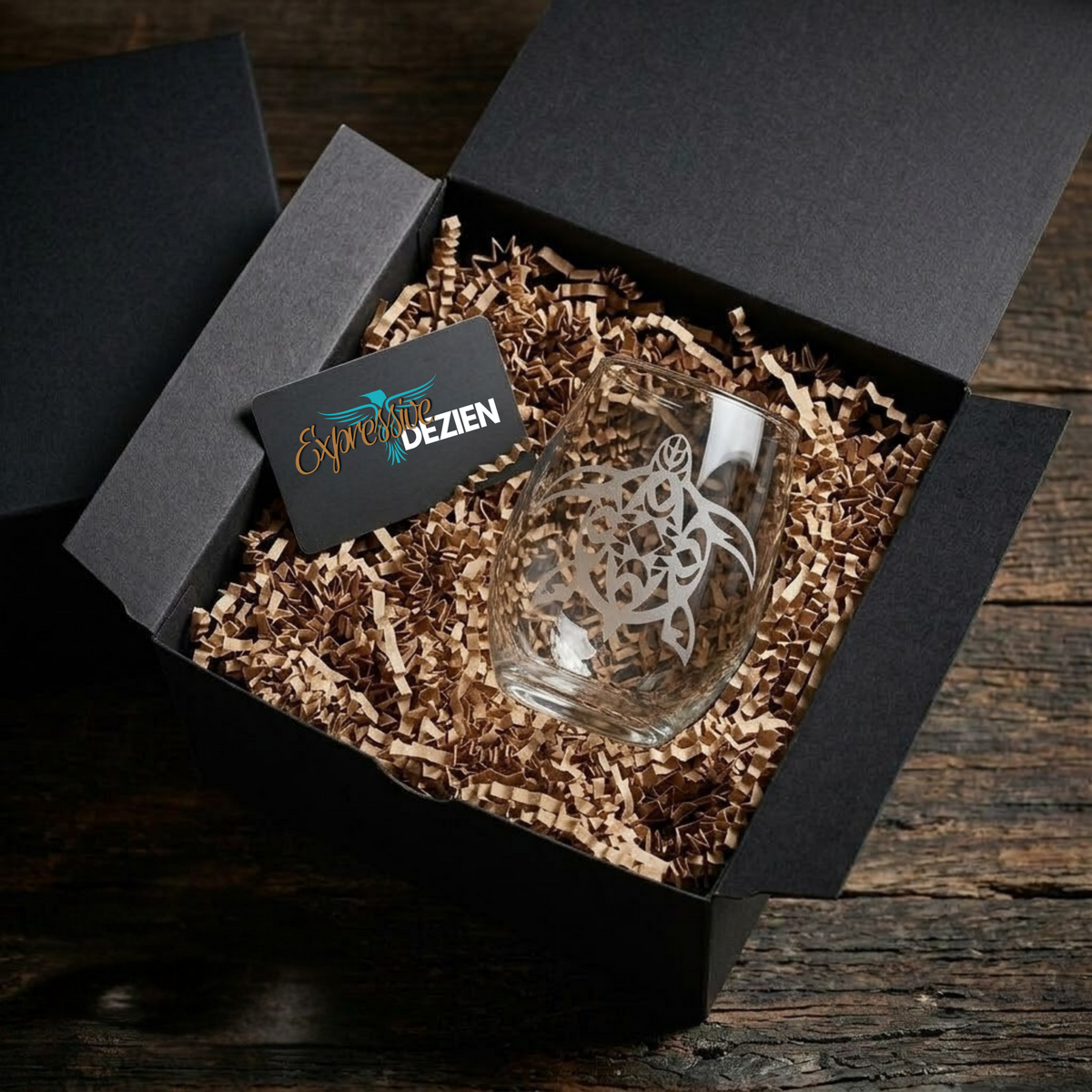 Glass with intricate design in a black gift box on a wooden surface
