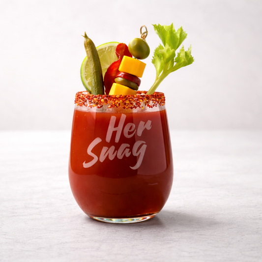 Her Snag 20.5oz etched stemless wine glass featuring a weighted bottom, styled as a Bloody Mary with a tajin rim and garnishes.