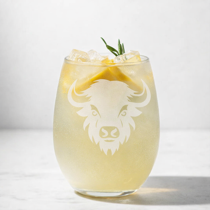Glass with a drink and ice cubes, featuring an engraved Bison design on a white background