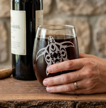 Hand holding a 20.5oz stemless wine glass with Tribal Turtle sandblasted carving
